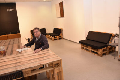 Stefan Wolters sitzt an einem Tisch aus Europaletten ind den neuen Räumen